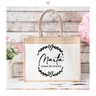Sacola personalizada bege com painel branco e texto Marta Dama de Honor, com decoração floral ao lado.