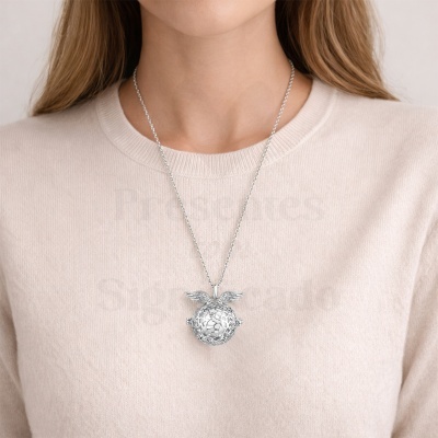 Colar prateado com pendente esférico com asas sobre camisola branca