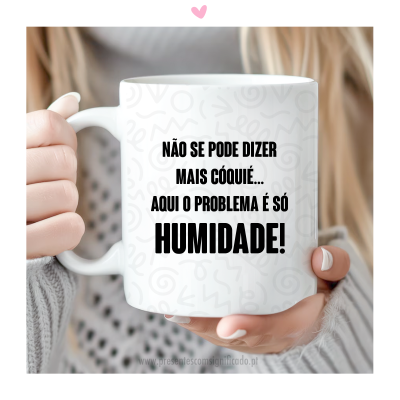 Caneca branca com texto humorístico sobre humidade em fundo cinza claro, segurada por uma pessoa.
