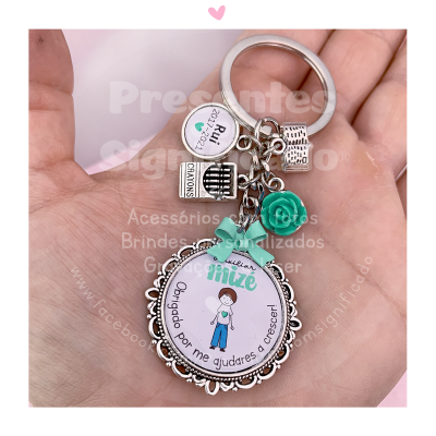 Chaveiro com pingente redondo e miniaturas metálicas na palma da mão