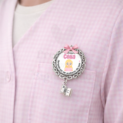 Broche prateado com laço cor-de-rosa e pendente de livro ABC sobre roupa rosa xadrez