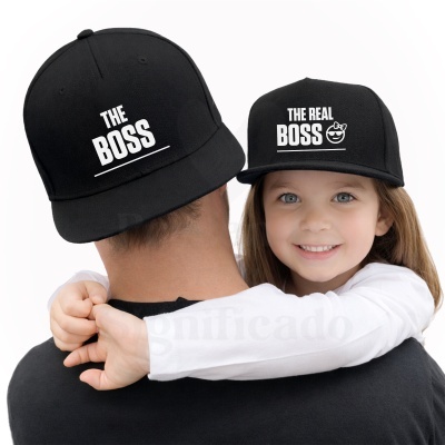 Duas bonés pretos com texto branco, um THE BOSS e outro THE REAL BOSS com ícone smiley, usados por adulto e criança.