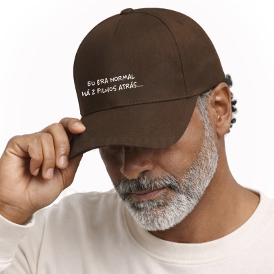 Homem a usar boné castanho com texto branco e camisola clara