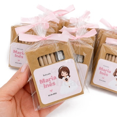 Conjunto de lápis em embalagem castanha com etiqueta personalizada para batizado e fita rosa.