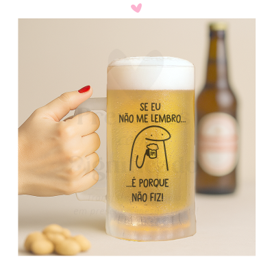 Copo de cerveja com texto e desenho sendo segurado por mão de unha vermelha