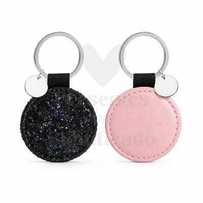 Dois chaveiros redondos, um preto com cristais brilhantes e outro rosa em tecido liso, com argola metálica e pequena placa redonda.