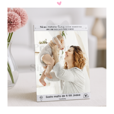 Espelho com moldura branca e texto em português com desenho de menina, em fundo neutro com vaso de flores rosas