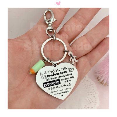 Chaveiro em forma de coração com texto para professoras e três penduricalhos coloridos na mão