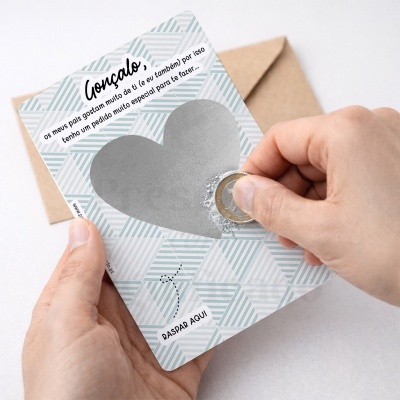 Cartão raspadinha com coração prateado e texto em português segurado por mãos com moeda para raspar