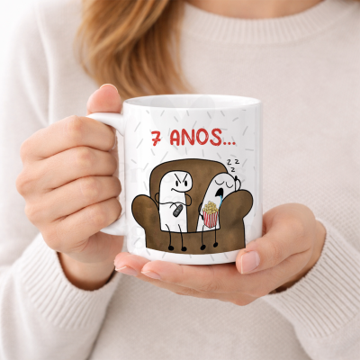 Caneca branca com ilustração de dois personagens num sofá e texto 7 ANOS