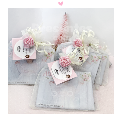 Lembrancinhas de batismo decoradas com flores rosa e embalagens transparentes com laços