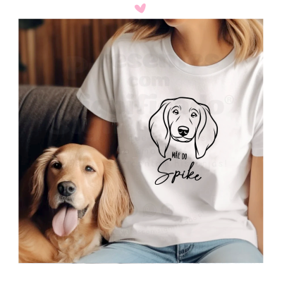 Camiseta branca com desenho de cão e texto 'MÃE DO Spike' ao lado de um cão Golden Retriever sentado num sofá