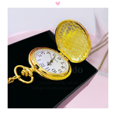 Relógio de bolso dourado aberto com mostrador branco dentro de caixa preta