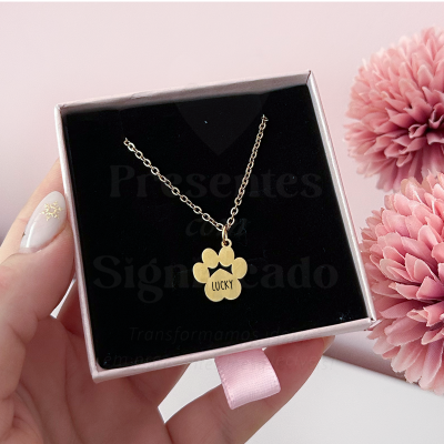 Colar dourado com pendente em forma de pata e a palavra LUCKY numa caixa de joias preta