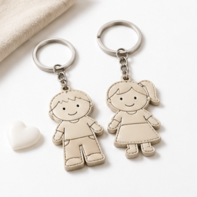 Dois porta-chaves boneco rapaz e rapariga bege com costuras, ao lado de pequeno coração branco
