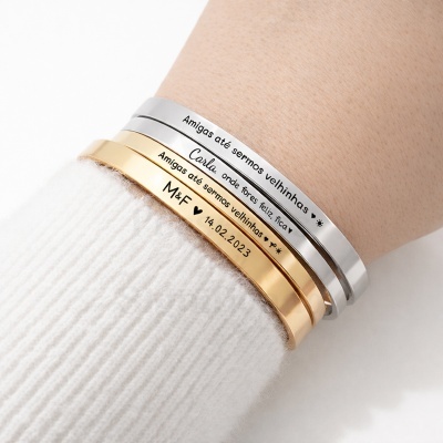 Pulseiras metálicas douradas e prateadas com gravações em português usadas no pulso