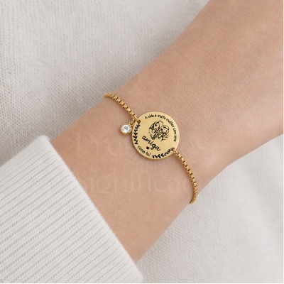 Pulseira dourada com pendente redondo gravado e pedente de pedra cristal na mão