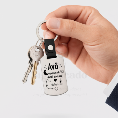 Chaveiro metálico com mensagem para avô e desenhos espaciais segurado por uma mão com fato azul