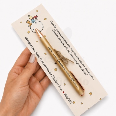 Caneta dourada com cartão ilustrado do Pequeno Príncipe e texto em português