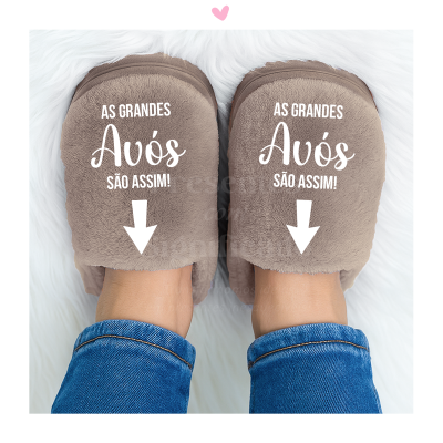 Chinelos castanhos com texto branco para avós, usados com calças de ganga sobre fundo branco.