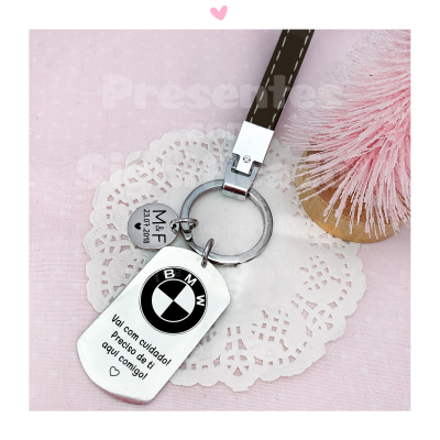 Porta-chaves metálico com logotipo BMW e pendente com texto em fundo rosa e renda branca.