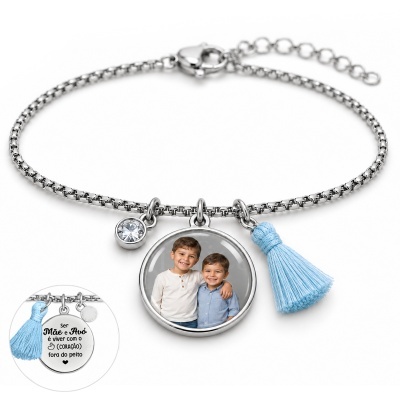 Pulseira prateada com pendente redondo com foto de duas crianças, pendente com pedra branca e tassel azul