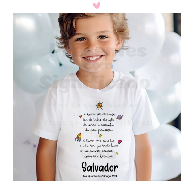 Criança sorridente com camisola branca e balões brancos ao fundo.