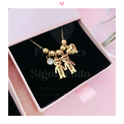 Colar dourado com pingentes de coração e figuras humanas numa caixa rosa
