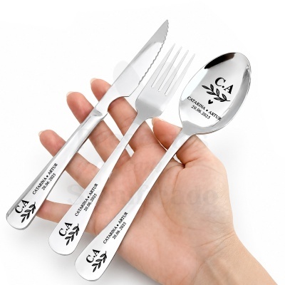 Conjunto de talheres em aço inoxidável com gravação personalizada segurados numa mE3o