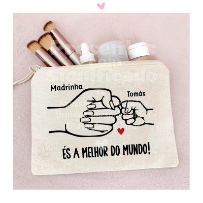 Necessaire bege com desenho de punhos a tocar e texto sentimental, com pincéis e frascos de maquilhagem ao redor