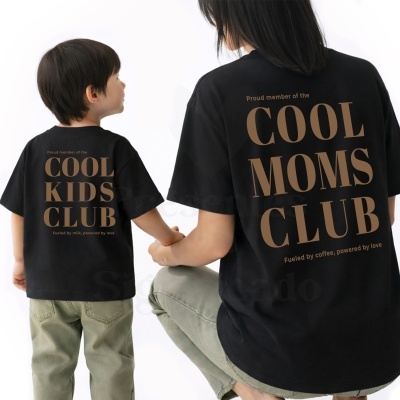 Duas t-shirts pretas com textos diferentes em castanho, uma para criança e outra para adulto.