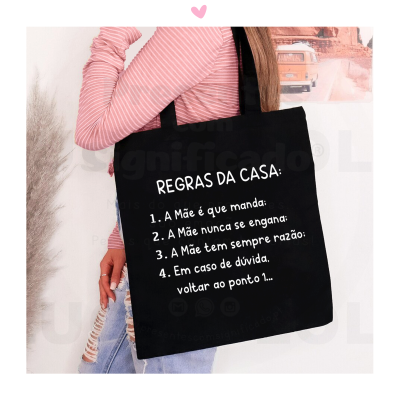 Saco de tecido preto com texto branco listado em português, usado por pessoa com camisola rosa às riscas e jeans rasgados