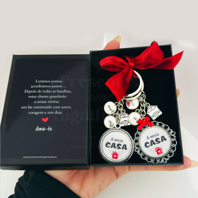 Porta-chaves com pingentes redondos e casa, laço vermelho e caixa com texto em português