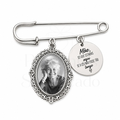 Alfinete de metal com foto a preto e branco e pendente com mensagem de homenagem