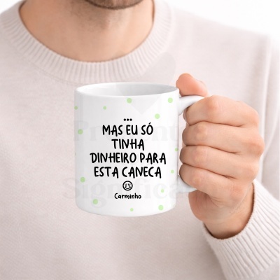 Caneca branca com bolinhas verdes e texto a preto em português, segurada por uma mão.