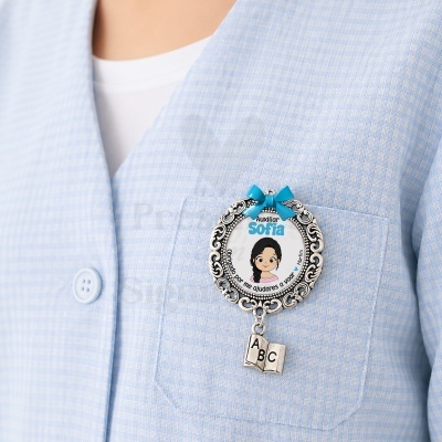 Broche redondo prateado com pendente de livro e texto personalizado em tecido azul claro