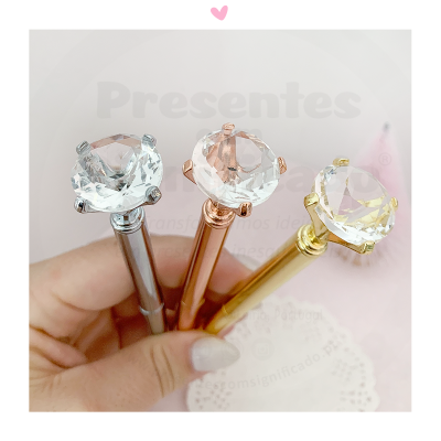 Três canetas metálicas com topo em pedra brilhante, seguradas por uma mão