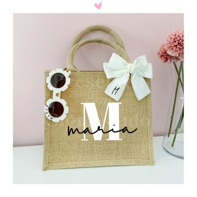 Saco de palha com laço branco, óculos de sol florais e flor cor-de-rosa no vaso