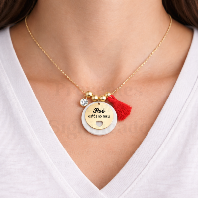 Colar dourado com pendente redondo e borla vermelha no pescoço de uma pessoa