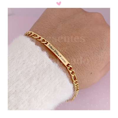 Pulseira dourada com gravação num pulso com camisola branca felpuda