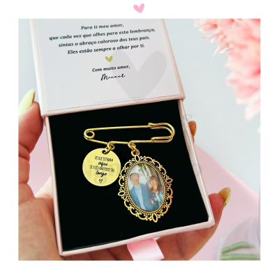 Alfinete de segurança dourado com foto e pendente gravado numa caixa de presente