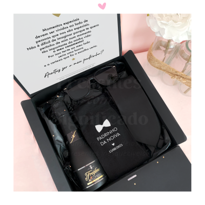 Caixa preta com garrafa de espumante, óculos escuros e caixa etiquetada para padrinho da noiva