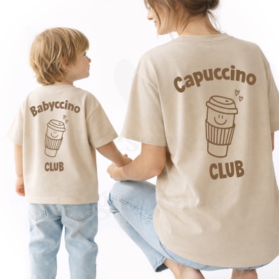 T-shirts bege com estampados castanhos de copos de café e textos Capuccino CLUB e Babyccino CLUB vistas pelas costas.