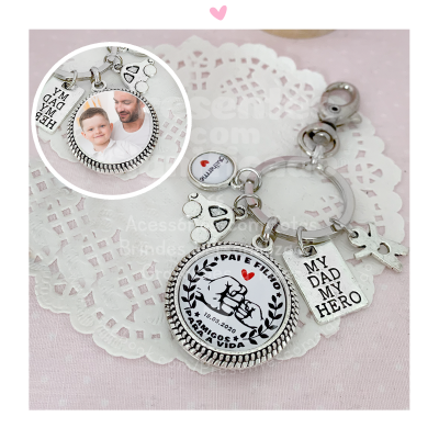 Porta-chaves metálico com pendentes, medalhas e textos emotivos sobre papel rendilhado branco