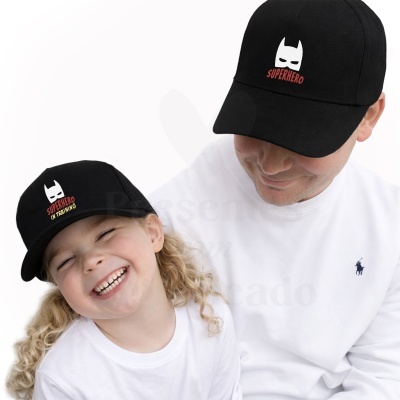 Criança e adulto com bonés pretos com texto SUPERHERO e SUPERHERO IN TRAINING