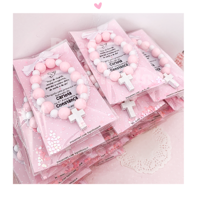 Pulseiras rosa e branca com cruz em embalagem cor-de-rosa