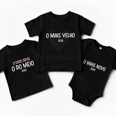 Três peças de roupa infantis pretas com texto branco sobre ordem de nascimento e anos
