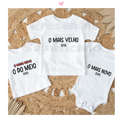 Três peças roupa bebé brancas com texto preto sobre tapete palha redondo