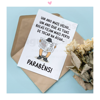 Cartão de felicitações com texto humorístico em português e envelope castanho sobre fundo azul claro, acompanhado de flores secas.