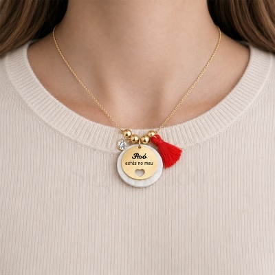 Colar dourado com pendente duplo e tassel vermelho em pescoço com camisola bege
